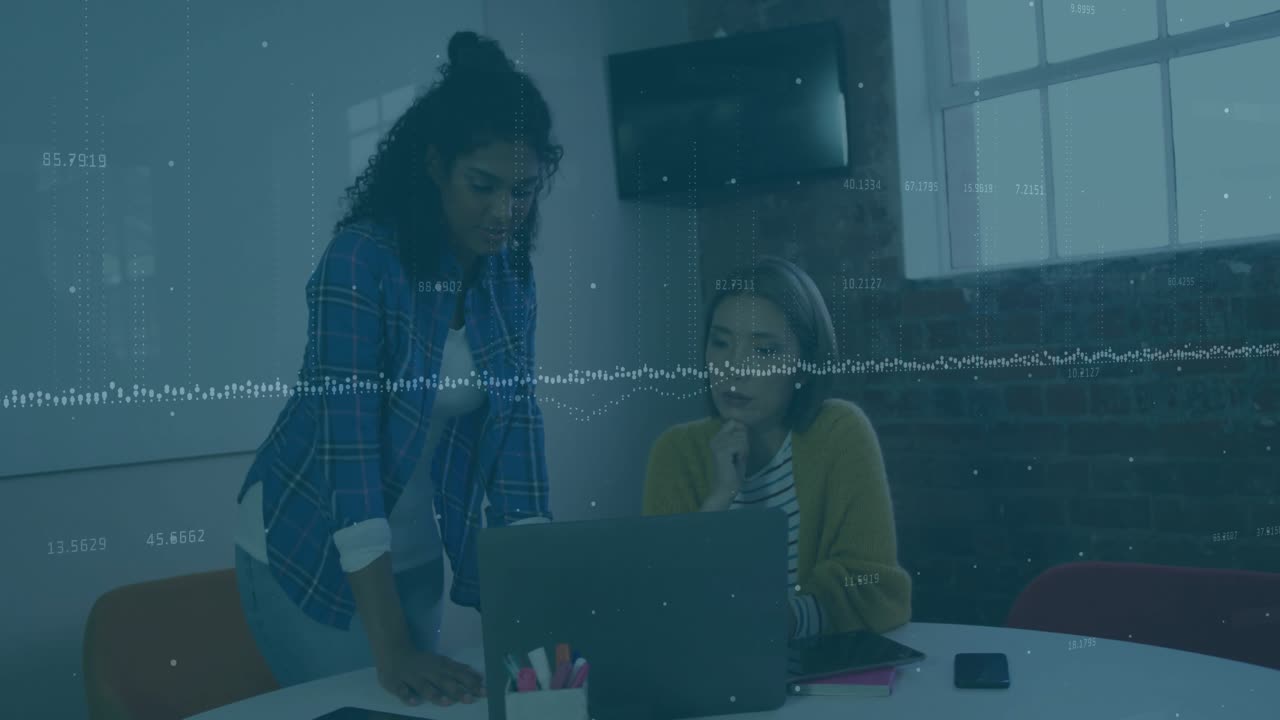 Two colleagues reviewing laptop one tapping trackpad initiating chart overlay in office meeting