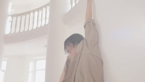 bottom view of contemporary male japanese dancer training dance moves leaning on the wall in the studio