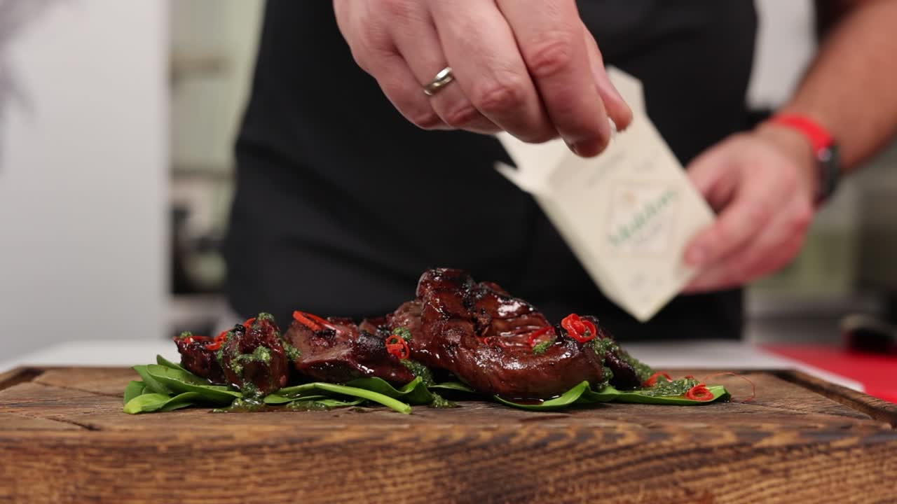 cocinero aderezando un filete a la parrilla con espinacas
