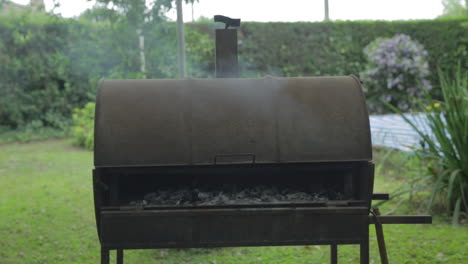 Barril-De-Barbacoa-De-Metal-Con-Carbón-Humeante-Asando-Carne-En-El-Interior-En-Un-Día-De-Verano