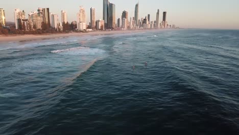 drone aerial pan up with stand up paddle boarders on ocean during sunrise