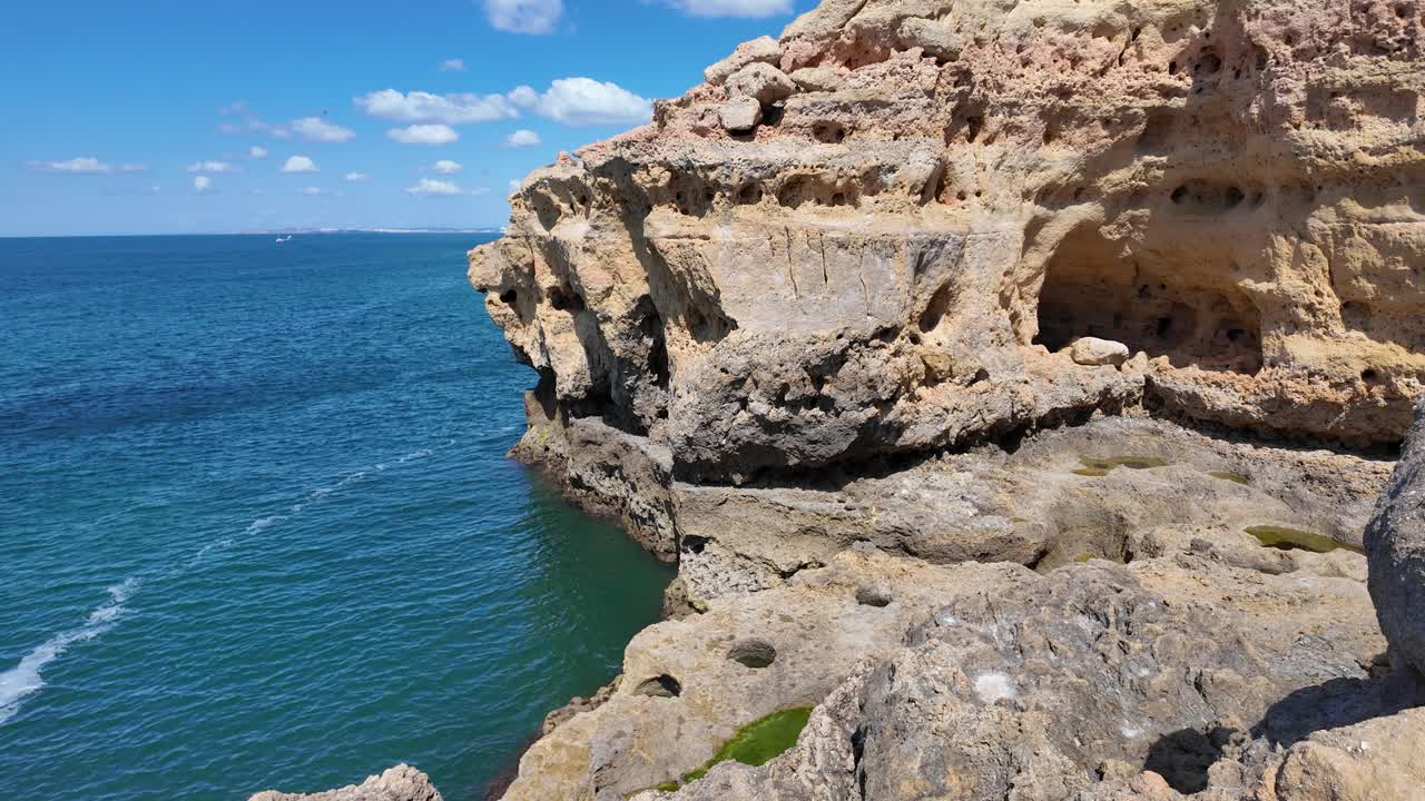 Breathtaking view of the rugged coastline with its eroded limestone cliffs and caves, meeting the vast expanse of the Atlantic Ocean in Carvoeiro, Portugal