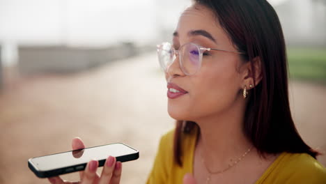 woman using voice assistant on smartphone outdoors