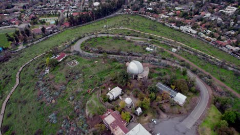 Spiralförmige-Luftaufnahme-Des-Calan-Hügels-Mit-Den-Schneebedeckten-Anden-Im-Hintergrund,-Santiago,-Chile