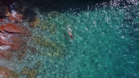 Toma-Aérea-De-Arriba-Hacia-Abajo-De-Una-Mujer-Nadando-En-Aguas-Turquesas-Claras