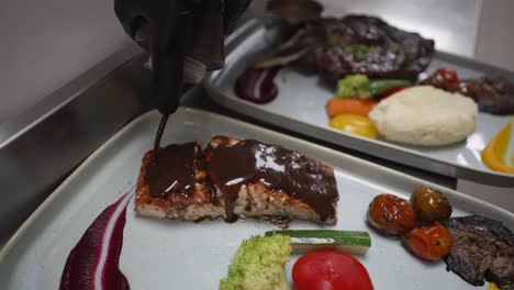 Chef-Pours-BBQ-Sauce-on-Grilled-Salmon,-Meal-in-Restaurant,-Closeup