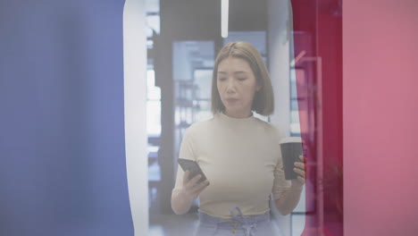 walking through office, woman holding coffee and phone with animation overlay
