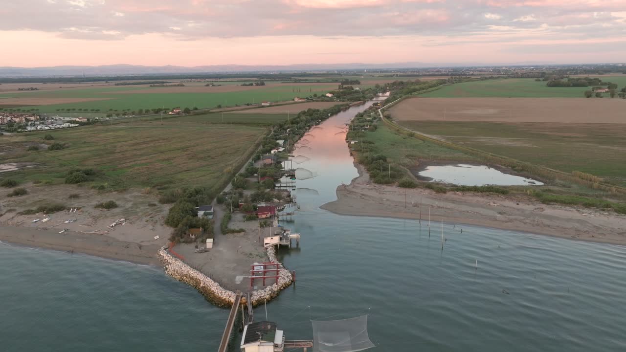 vista aérea de cabañas de pesca a orillas del estuario al atardecer, máquina de pesca italiana, llamada "trabucco", lido di dante, ravenna cerca del valle de comacchio