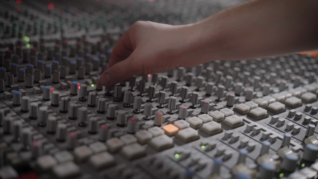 soundman está ajustando el brazo de control en un panel de un grabador multitrack moderno en un estudio de grabación de audio
