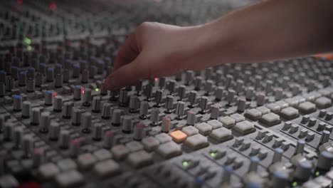 soundman is adjusting control arm on a panel of a modern multitrack recorder in an audio recording studio