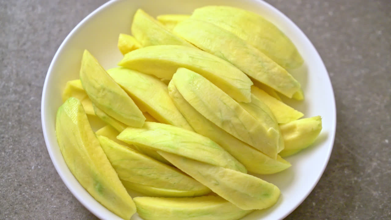 mango verde fresco y dorado en rodajas en un plato