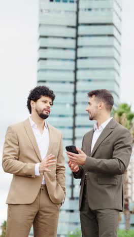 two businessmen in suits talking outside a modern building