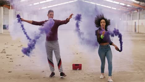 dancers in an empty warehouse holding smoke grenade