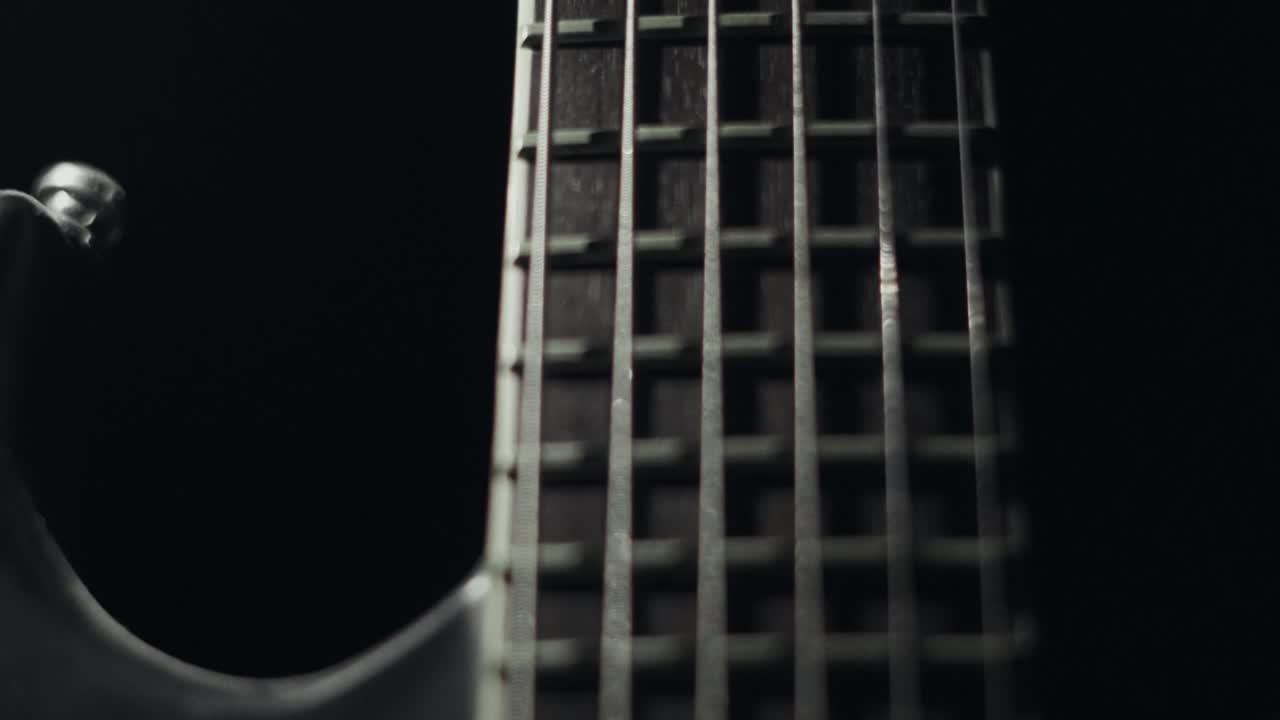 Light revealing guitar strings in complete darkness