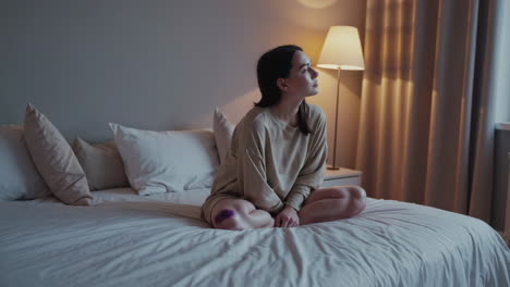woman sitting on bed with injured knee