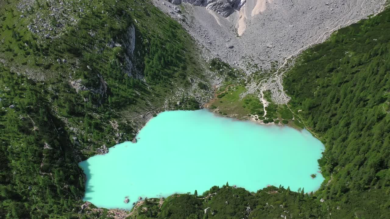 Lake Sorapis bright turqoise water in the Dolomites Italy, tilt down aerial