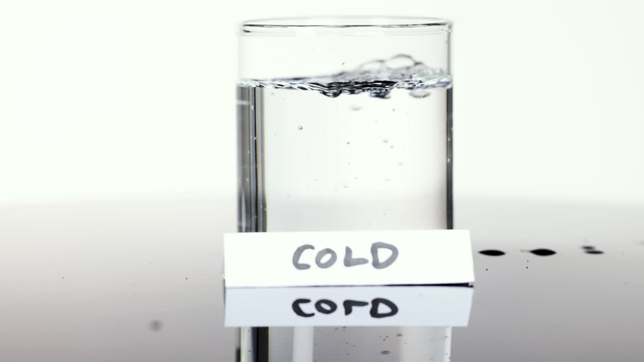 Cold water poured into clear glass, creating bubbles, in bright studio lighting, static camera