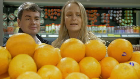 man and woman choosing oranges