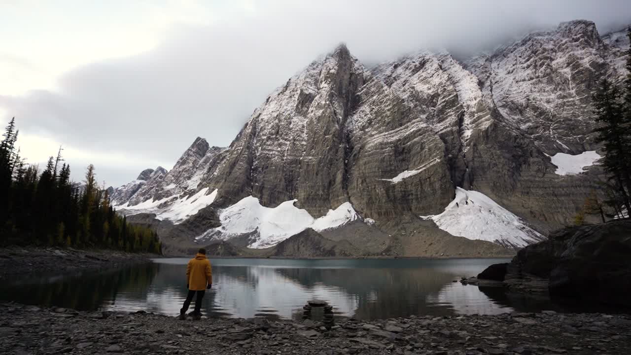 el hombre de la aventura de mochilero frente al lago floe en el parque nacional de kootenay