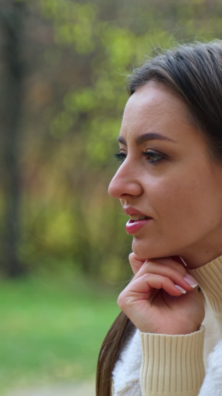 Beautiful young outdoor communication. Pretty lady with phone sitting in park. Vertical video