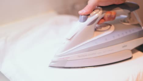 man ironing a white dress shirt to get ready for work