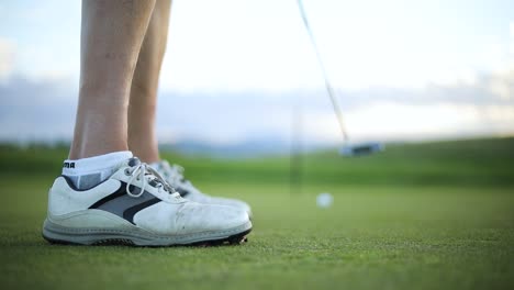 slow motion shot of a man making a putt on a putting green