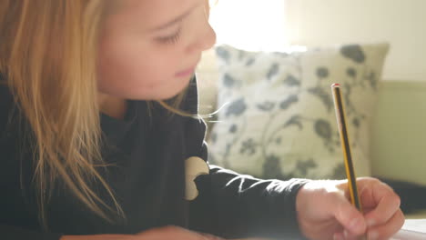 Girl-Sitting-At-Table-Indoors-Doing-Homework