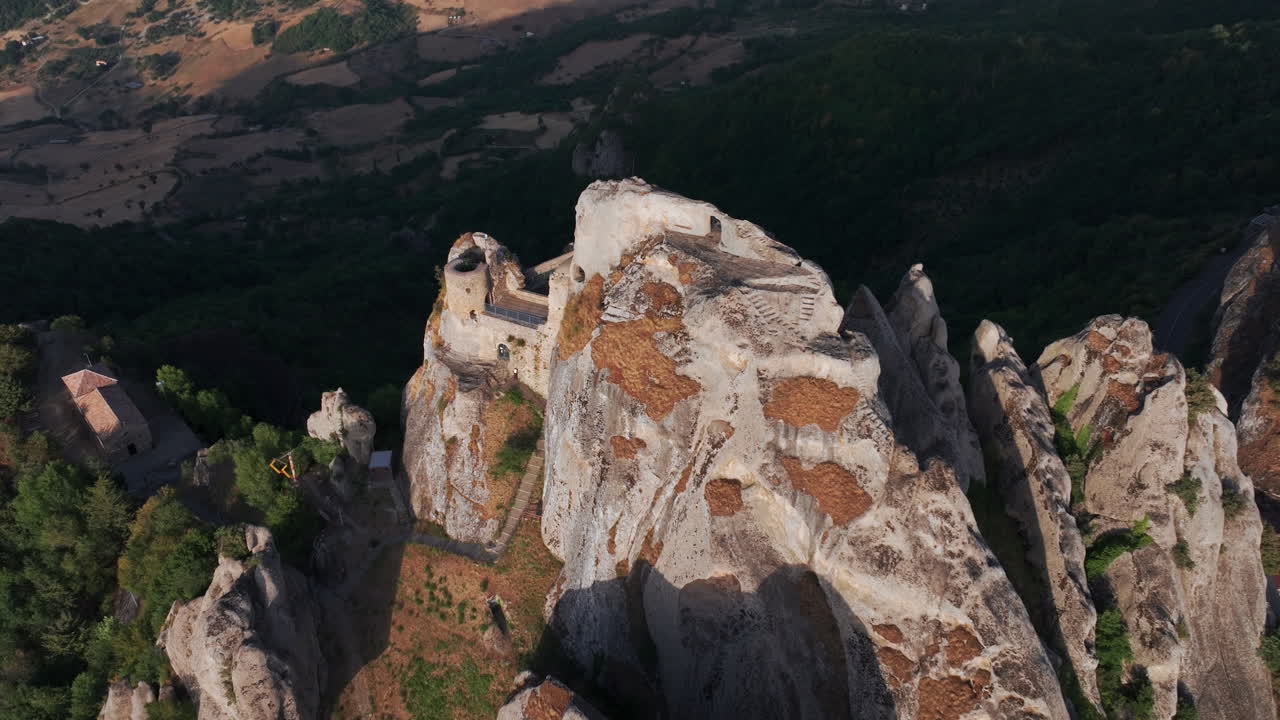 Aerial drone of Pietrapertosa, Italy—mountain village built into rocky peaks, terracotta roofs, sweeping valley views. Ideal for travel, tourism, culture, and cinematic landscape stock footage