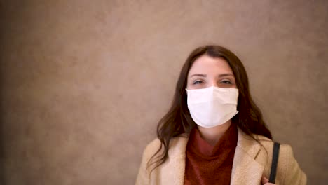 beautiful girl wearing protective medical mask and fashionable clothes looks at camera and be happy