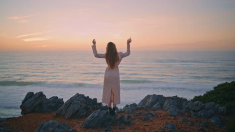 serene girl enjoying sunset nature raising hands back view. woman looking marine