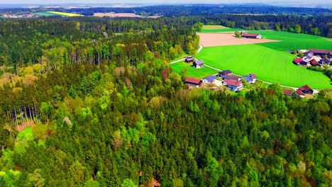 Vista-Aérea-Del-Pintoresco-Pueblo-Rural-Rodeado-De-Bosques-Y-Campos-Verdes