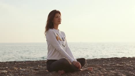 woman meditating on the beach at sunset