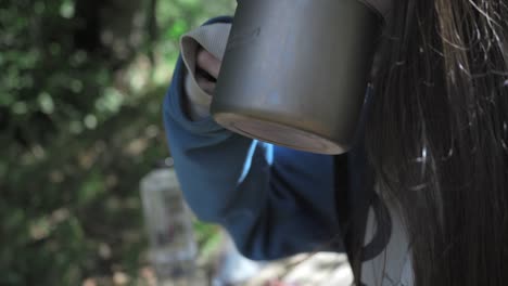 Mujer-Bebiendo-Una-Sopa-En-La-Naturaleza,-Al-Aire-Libre,-Acampando