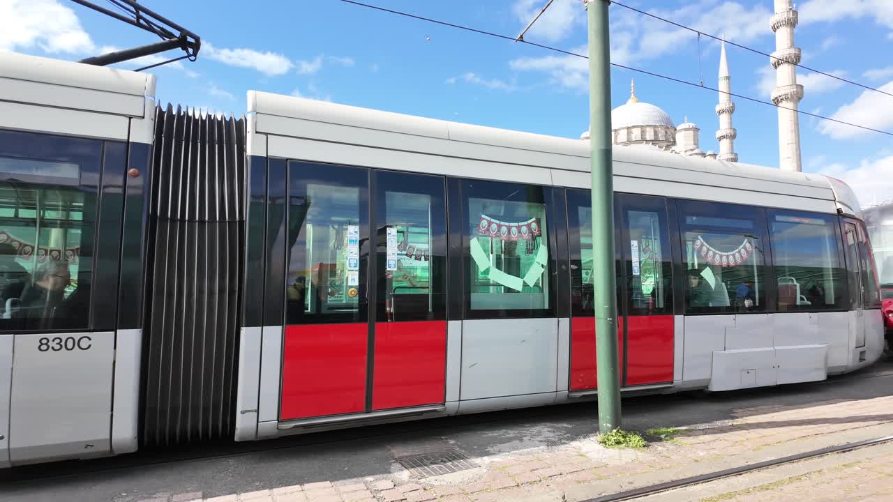 Tranvía moderno circulando por la ciudad con una mezquita de fondo
