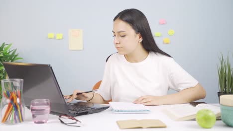 female student working between paper and laptop.