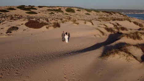 newlywed couple walking on sandy sea coast