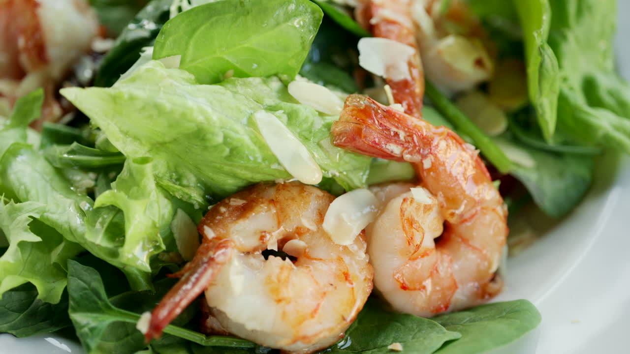 Close up of shrimp served on a fresh green salad with toppings