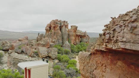 drone flies slowly past rock formations in desert landscape in cederberg wilderness area in south africa - mountains can be seen in the background