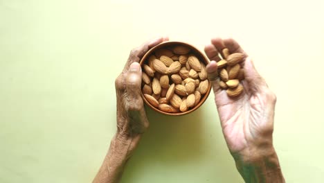 Elderly Hands Holding a Bowl of Almonds