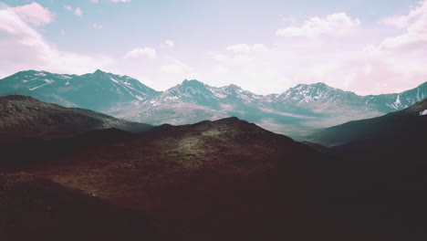aerial over valley with snow capped mountains in distance