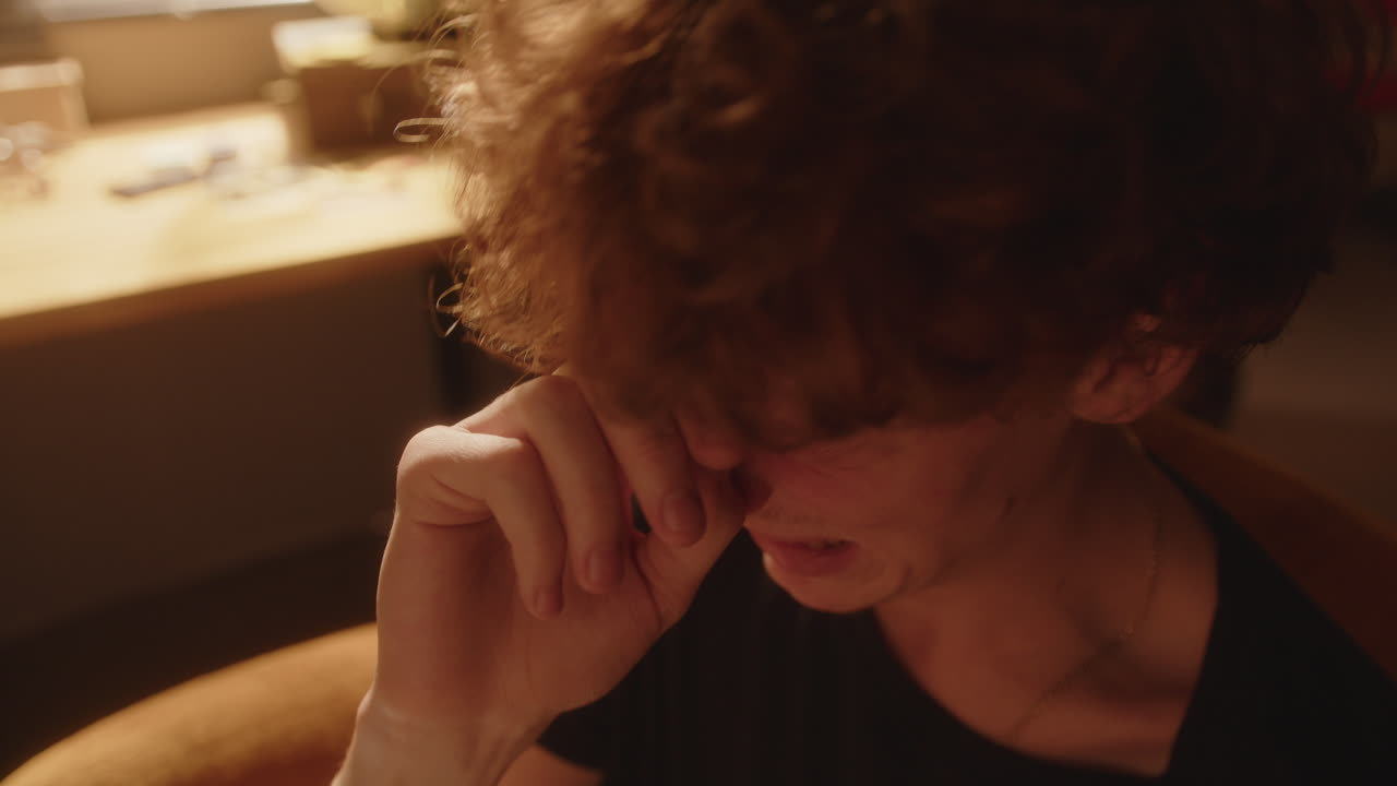 joven desesperado llorando y secando sus lágrimas en una habitación iluminada por el sol