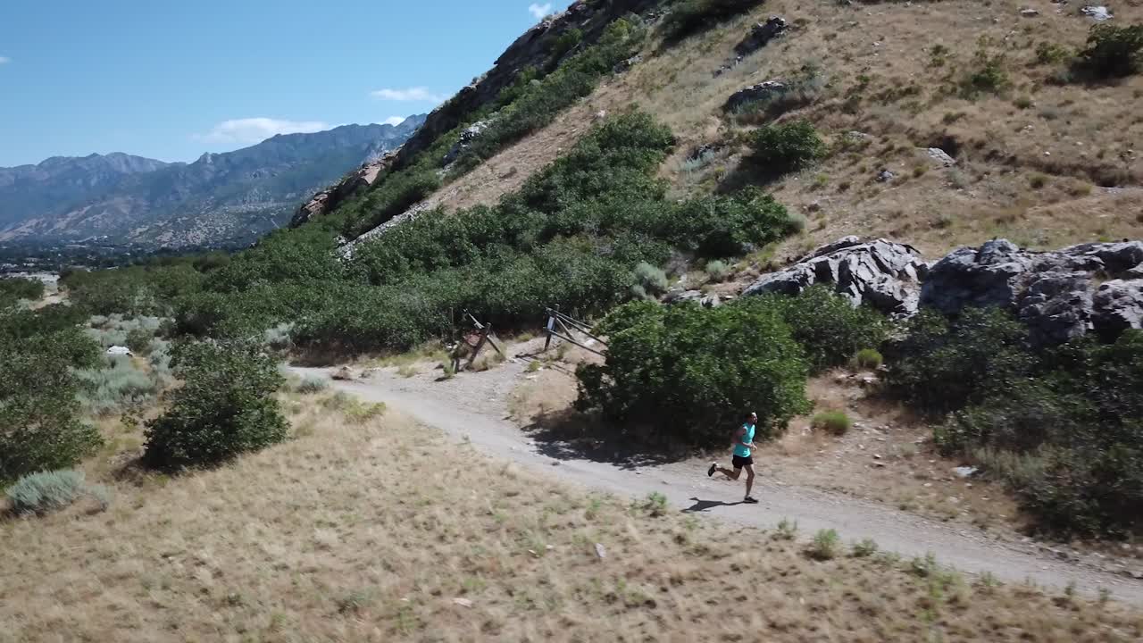 disparo de dron siguiendo a un hombre activo corriendo en los senderos de montaña al aire libre de wasatch sobre draper city, utah-1