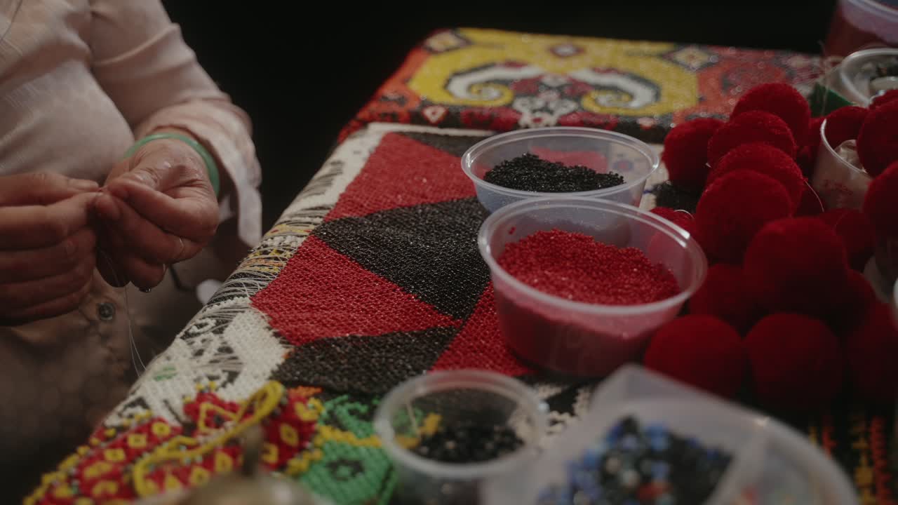 Sarawakian indigenous traditional lady creating beadwork craft on a table full of colourful beads