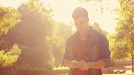 Hombre-Guapo-Usando-Su-Teléfono-Inteligente-En-El-Parque