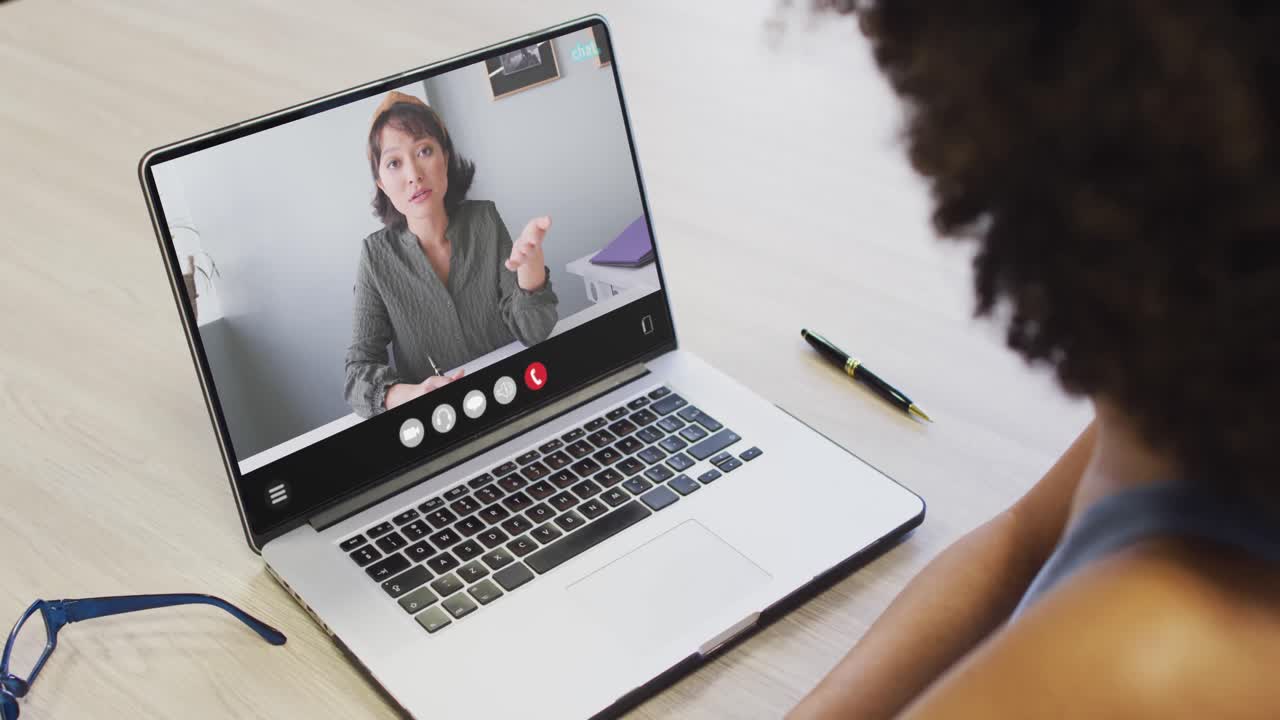 African american woman using laptop for video call, with business colleague on screen