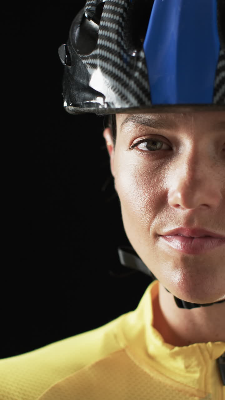 Vertical video: Wearing helmet, cyclist in yellow jersey looking determined, close-up portrait