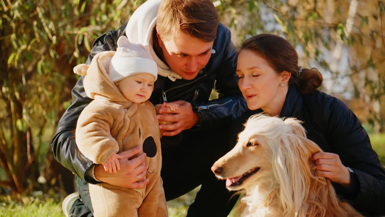 Et gledelig familieøyeblikk: Setter pris på tiden sammen med deres bedårende baby og elskede hund i en fredfull utendørs setting på en varm og solrik dag