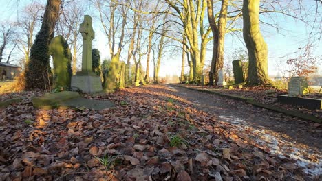 FPV-flying-around-headstones-in-snowy-winter-sunrise-churchyard-cemetery-during-golden-hour