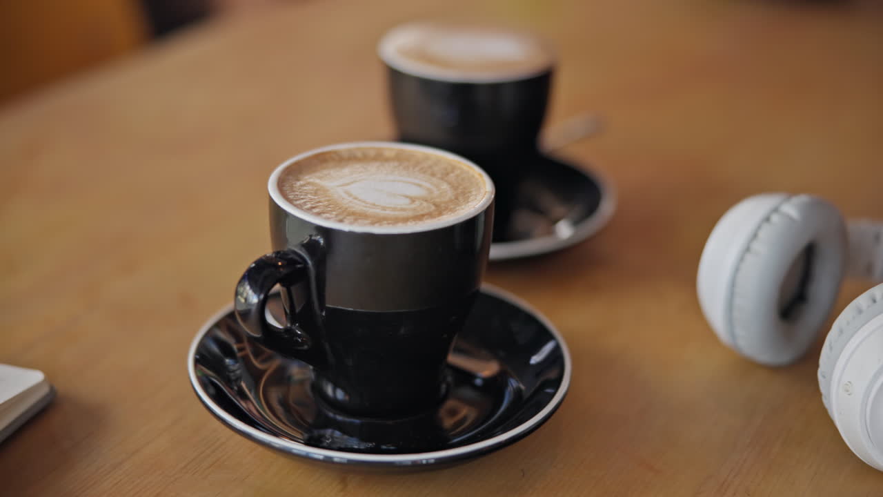 café, portátil y auriculares en la mesa