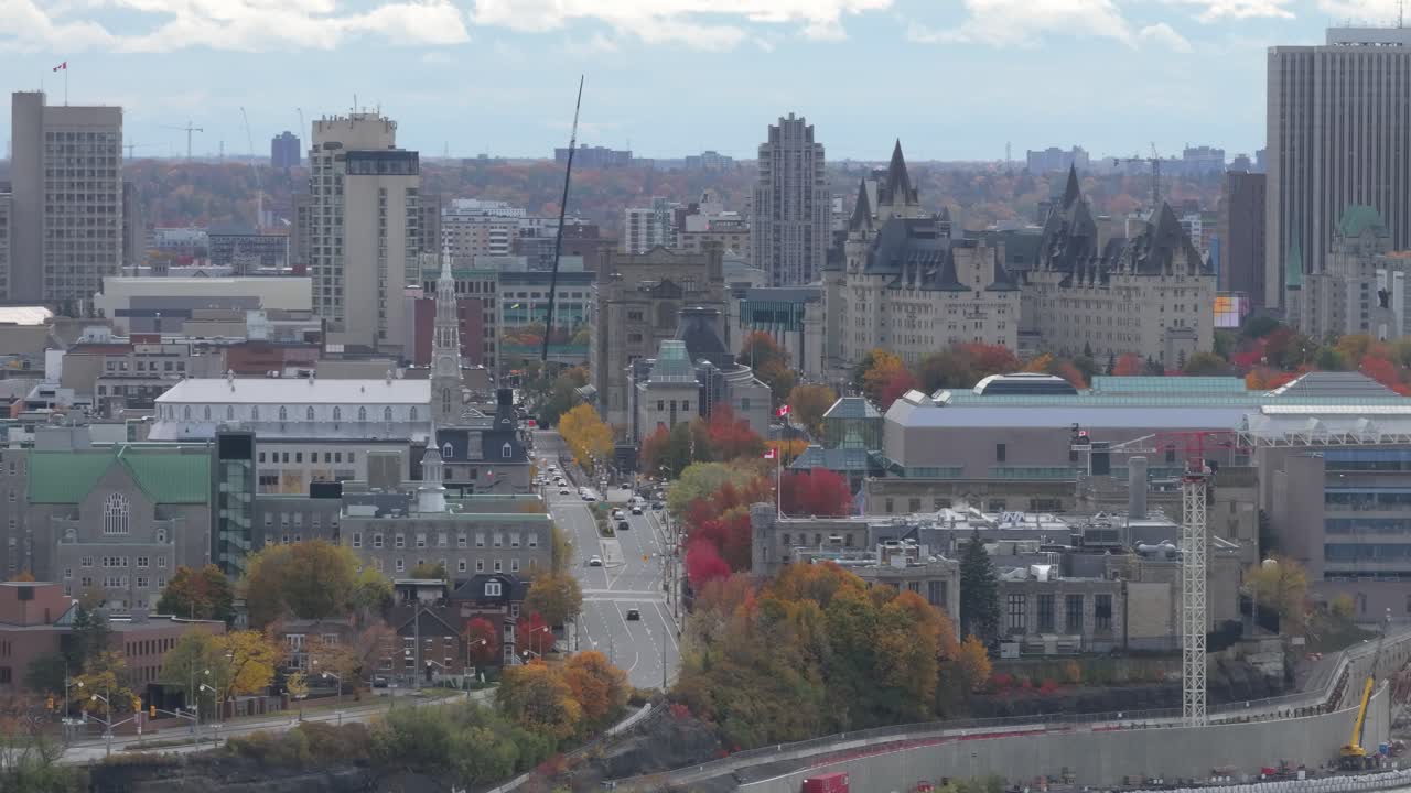 Ampia prospettiva aerea del fiume Ottawa che scorre sotto il Ponte Alexandra, con lo skyline della città e il Parlamento sullo sfondo.